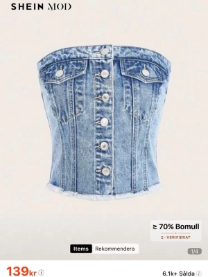 Blå jeans tubtopp med knappar - Säljer en snygg blå jeans tubtopp från SHEIN med knappar framtill och två dekorativa bröstfickor. Toppen har rå kant nertill och är tillverkad i bomullsmix. Perfekt för dig som vill ha en trendig och edgy look.