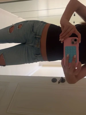 Ljusblå ripped jeans  - Säljer ett par ljusblå jeans med slitningar på både lår och knä. Jeansen har klassisk femficksdesign och smal passform. Perfekta för en trendig och avslappnad look. Storlek: W26, L31