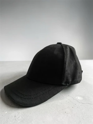 Svart Fendi keps - En stilren svart keps med böjd skärm och justerbar rem bak. Tillverkad i ett mjukt tygmaterial som ger en clean och enkel look. Perfekt för dig som vill ha en basic accessoar som funkar till det mesta.