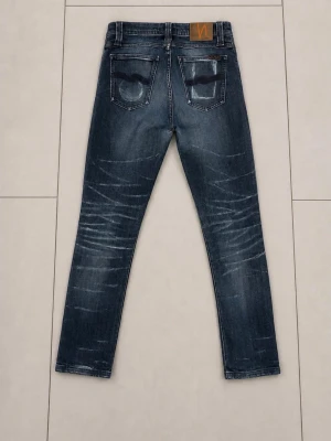 Nudie Jeans 30/34 - Säljer ett par blå slim fit jeans från Nudie Jeans med snygga slitningar och tvättade detaljer. Klassisk femficksmodell med normal midja och raka ben. Jeansen har en patch i läder bak i midjan och kontrastsömmar. Perfekta för en avslappnad och trendig look.
