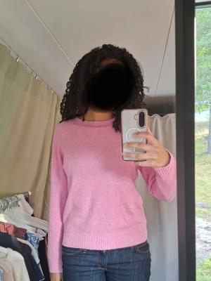Ljusrosa stickad tröja - Mysig rosa stickad tröja med rund halsringning och långa ärmar. Tröjan har en enkel, klassisk design med ribbade muddar vid ärmslut och nederkant. Perfekt att matcha med jeans för en avslappnad look.