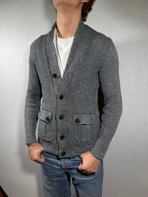 H&M kofta XS - Hej och välkommen till byTorén. Detta är en kofta från H&M i storlek XS med normal passform. Modell på bild är ca 182, 67kg. Plagget är i bra skick men saknar varsin knapp vid fickorna, se bild 1. Tveka inte på att höra av dig, även om det skulle vara minsta lilla;)
