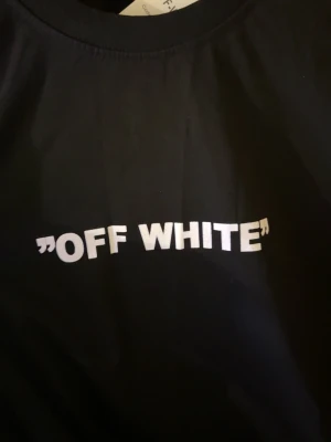 Svart Off White t-shirt med Bart-tryck - Cool svart t-shirt med stort färgglatt tryck av Bart Simpson på framsidan och texten 'OFF WHITE' både fram och bak. T-shirten har rund hals och korta ärmar. Materialet känns mjukt och skönt, perfekt för dig som gillar streetwear och unika prints.