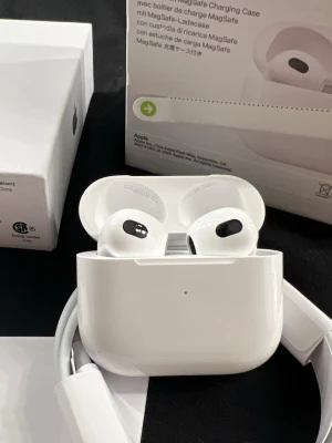 Alrpods gen 3 - Snygga trådlösa hörlurar från Apple i klassisk vit färg. Kommer med laddningsetui och laddningskabel. Hörlurarna har en stilren och kompakt design i blank plast, perfekt för musik, samtal och vardagsbruk. Laddningsetui med magnetlock ingår.