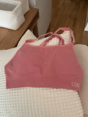 Rosa ribbad sport-bh från ICANIWILL - Ribbad sport-bh från ICANIWILL i storlek M med axelband som korsas i ryggen. Bh:n ät stretchig och skön. 50 kr!