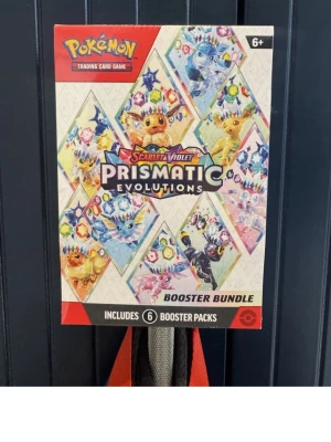 Pokémon Prismatic Evolutions Booster - Pokémon Scarlet & Violet Prismatic Evolutions Booster Bundle med färgglad design och flera populära Pokémon på framsidan. Innehåller 6 booster packs med samlarkort. Perfekt för dig som vill utöka din samling eller spela Pokémon Trading Card Game. NO RETURNS IF IF THE SEAL IS RIPPED SINCE THE ITEM IS WORTHLESS