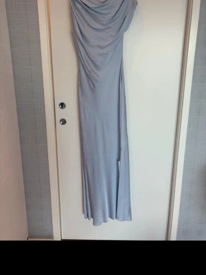Twist & Tango Vanessa Satin dress  - Elegant ljusblå långklänning med draperad överdel från Twist & Tango.  Aldrig använd med alla lappar kvar. Klänningen är från den här säsongen. Klänningen har en figurnära passform och är tillverkad i ett mjukt, glansigt material som ger en lyxig känsla. Perfekt för speciella tillfällen när du vill sticka ut. Nypris är 2800kr 