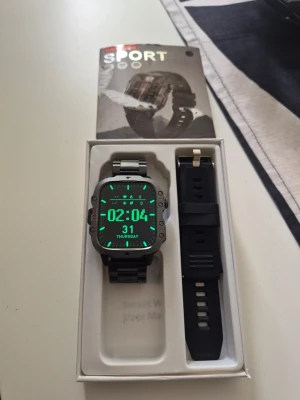 Sportig smartklocka med extra armband - Snygg och robust smartklocka från DAORKOW med fyrkantig display och metallarmband. Klockan kommer med ett extra svart silikonarmband och laddkabel. Perfekt för dig som gillar sportig design och vill ha flera armbandsalternativ. Displayen har tydlig digital tidvisning.