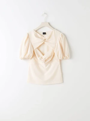 Topp med puffärm - Trendig creamfärgad topp med puffärmar och två dekorativa knyt framtill som skapar en öppen detalj över bröstet. Toppen har en figurnära passform och är tillverkad i ett mjukt material som ger en lyxig känsla. .