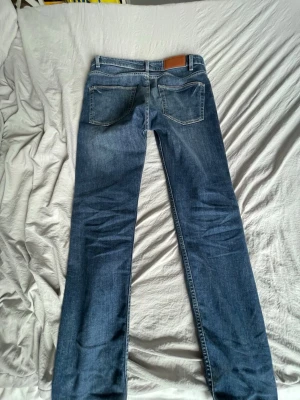 Blå regular fit jeans Dressmann - Snygga blå jeans från Dressmann i regular fit-modell. Klassisk femficksdesign, raka ben och detaljer i kopparfärg. Tillverkade i slitstark denim med kontrastsömmar och bälteshällor. Perfekta för en avslappnad och stilren look. Använd enbart fåtal gånger p.g.a fel storlek. Är inga slitningar eller fläckar, mycket bra skick!