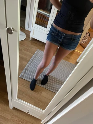 Mörkblå jeansshorts från Hollister - Säljer ett par klassiska mörkblå jeansshorts från Hollister med fem fickor och snygga kontrastsömmar. Shortsen har låg midja och råa kanter nedtill för en avslappnad look. Dem är typ storlek S eller Xs