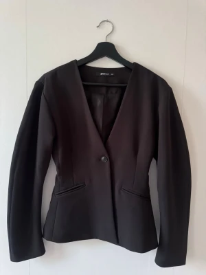 Svart kavaj från Gina Tricot XXS - Figursydd svart kavaj från Gina Tricot i storlek XXS. Kavajen har en djup V-ringning, enkel knappstängning och två fickor framtill. Pris kan alltid diskuteras 💕 Nypris 799kr