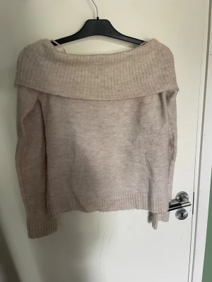 Beige off shoulder stickad tröja - Mysig beige stickad tröja från Gina Tricot med bred off shoulder-krage och ribbade muddar. Perfekt för dig som gillar en avslappnad men ändå trendig look. Materialet är mjukt och ger en skön känsla hela dagen.