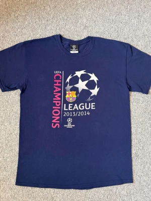 UEFA Champions League Barcelona - Säljer en marinblå t-shirt med tryck från UEFA Champions League 2013/2014 och FC Barcelona-logga, 100% cotton. Hör av dig vid frågor och behova av fler bilder!🤗🤗