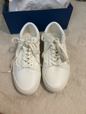 Vita detaljerade Vans  - Snygga vita sneakers i lågt modell med klassisk gummisula och coola spetsdetaljer på sidorna. Skorna har vita snören och ovandel i läderimitation som ger en clean och fräsch look. Perfekta för dig som gillar stilrena och trendiga skor. Helt nya och oanvända. Nypris 1200 kr☺️