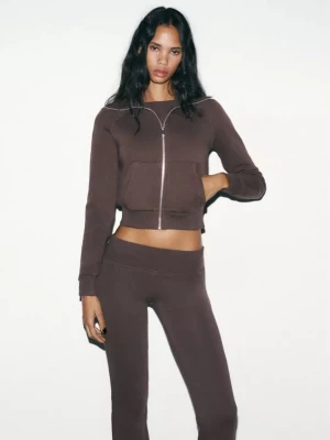 Brunt loungewear-set med ziptröja - Mysigt loungewear-set i brun färg med croppad ziptröja och matchande byxor. Tröjan har dragkedja framtill och stora fickor, byxorna är höga i midjan och har en smal passform. Perfekt för chill dagar hemma.