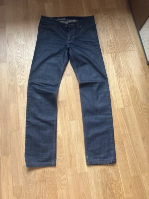 Esprit raka ”jam fit” waxed jeans. - Snygga mörkblå jeans med rak passform och klassiska fem fickor. Jeansen har kontrastsömmar i orange och är tillverkade i ett robust denimtyg. Ett lager vax på. 