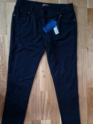 Svarta leggings från ARMEO - Snygga svarta leggings från ARNEO med smal passform och klassisk midja. Byxorna har fejkfickor fram och är tillverkade i ett stretchigt material som sitter skönt. Perfekta för dig som vill ha en enkel och stilren look.