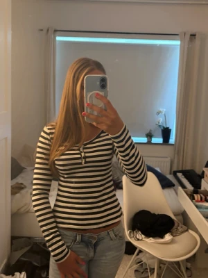 Randig långärmad topp med knappar - Snygg långärmad topp med svartvita ränder i storlek xs/ 34. Modellen är figurnära med knappar vid halsringningen som är uppknäppbara. 💗