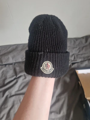 Moncler mössa  - Äkta moncler mössa. Jag säljer den för att jag inte använder den så mycket längre och för att den tyvärr inte passar mig längre. Tvättlappen är avklippt då den störde mig och qr koden fungerar. Ni får gärna komma med andra prisförslag