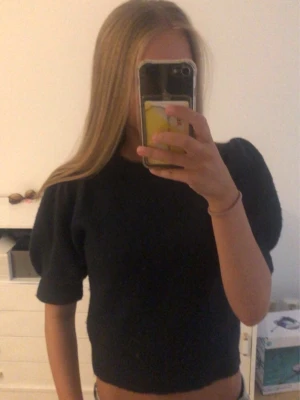 Mörkblå stickad topp med puffärm - Snygg mörkblå stickad topp med puffiga korta ärmar och rund hals. Modellen är croppad och har en enkel, stilren design som passar till mycket. Storlek 146/152 men är som xxs 🩷