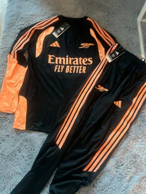 Arsenal 26/27 tränings kit  - Ett Arsenal tränings kit 26/27 tröja + byxor med fickor! Storlek L helt nytt