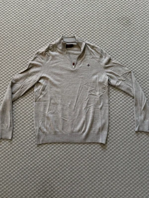 Ziptröja från Morris  - Snygg ljusbeige tröja från Morris med halv dragkedja och ståkrage. Tillverkad i mjuk bomull och har en diskret broderad logga på bröstet. Perfekt för en clean och stilren look.