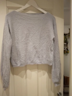 Ljusgrå / ljus blågrå fluffig jättemycket stickad tröja, S-M - Mysig ljusgrå/ljus blågrå stickad tröja med fluffig textur och avslappnad passform. Tröjan har långa ärmar och bred halsringning, perfekt för att hålla värmen under kyliga dagar. Materialet känns mjukt och skönt mot huden. Strlk ca S-M. Felfri.