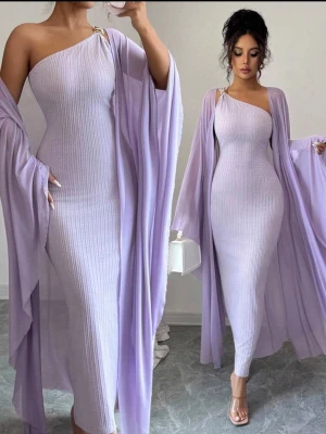 Ljuslila oneshoulder långklänning - Supersnygg ljuslila oneshoulder långklänning med ribbad struktur och matchande svepande sjal. Klänningen har en elegant, figurnära passform och är perfekt för dig som vill sticka ut. Materialet ser mjukt och stretchigt ut, vilket ger en bekväm känsla.