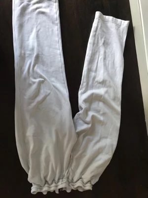 Vita mjukisbyxor från Hollister - Säljer ett par vita mjukisbyxor från Hollister med broderad logga på ena benet. Byxorna har resår i midjan för en skön och avslappnad passform. Tillverkade i mjukt och bekvämt material, perfekta för chill dagar.