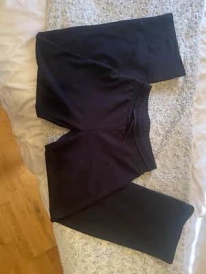 Svarta mjukisbyxor med dragsko - Ett par klassiska svarta mjukisbyxor med resår i midjan och dragsko för skön passform. Tillverkade i mjukt och stretchigt material som passar perfekt för chill dagar hemma eller när du vill vara bekväm. Raka ben och enkel design utan synliga loggor.
