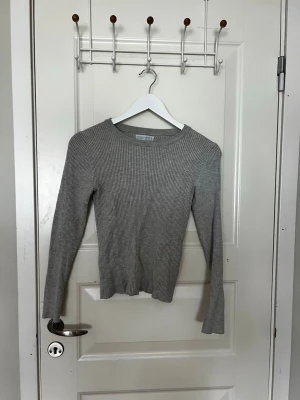Grå ribbad tröja från Primark - Säljer en grå långärmad ribbad tröja från Primark. Tröjan har rund halsringning och är figurnära i modellen.