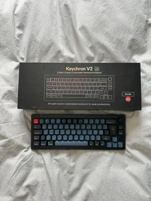 Keychron V2 mekaniskt tangentbord - Säljer ett Keychron V2 mekaniskt tangentbord med nordisk layout. Tangentbordet har en kompakt design med svarta och gråa tangenter samt en röd escape-tangent. Perfekt för dig som vill ha ett snyggt och anpassningsbart tangentbord till datorn.