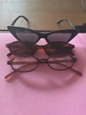Tre trendiga solglasögon i olika former - Säljer tre par solglasögon: ett par svarta cat-eye, ett par bruna med mönstrad båge och ett par ovala i bruntonat transparent blue light glas . Perfekta accessoarer för att lyfta din stil och skydda ögonen mot solen. 