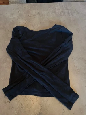 Svart långärmad topp med rund hals - En enkel svart långärmad topp med rundad halsringning. Toppen har en smal passform och är tillverkad i ett mjukt, stretchigt material som känns bekvämt mot huden. Perfekt att styla med jeans eller kjol för en clean look.