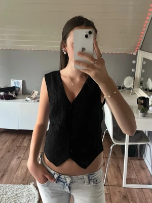 Svart ärmlös topp med knappar stl. S - Säljer denna snygga V-ringade toppen från H&M, har andvänds ca 2-3 gånger så den är i nytt skick