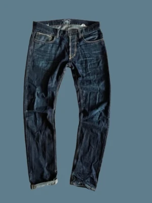 Gilded Age selvage jeans - Snygga mörkblå jeans med raka ben och kontrastsömmar. Klassisk femficksmodell med uppvikta benslut och detaljerade bakfickor. Jeansen har en tidlös look och är tillverkade i kraftigt denimtyg. Nypris är mellan 3500-4000kr. Fråga gärna om ni har några frågor!