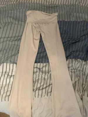Ljusbeige utsvängda leggings - Säljer ett par ljusbeige leggings med utsvängda ben och hög midja. Mjukt och stretchigt material som sitter skönt på kroppen. Har använt ungefär 3 gånger men fick bleknings fläckar på annars helt nya.