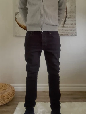  Nudie Jeans Lean Dean - Svarta jeans från Nudie Jeans i modellen 31/30. Jeansen har klassisk femficksdesign, svarta sömmar och Nudie Jeans logga på bakfickan. Tillverkade i ekologisk bomull med en straight passform som sitter snyggt. Perfekta för dig som gillar stilrena och enkla jeans.