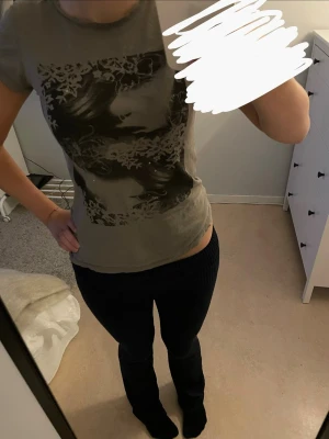t-shirt med tryck från Gina Tricot - Säljer en grågrön t-shirt från Gina Tricot i storlek S. T-shirten har ett stort svart tryck framtill med konstnärlig design. Modellen är kortärmad och har en klassisk rund halsringning. Perfekt till jeans eller kjol för en cool vardagslook. har typ målarfärg eller något på ena axeln men inget som syns, se sista bilden !!