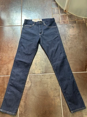 Mörkblå slim fit jeans från East west  - Snygga mörkblå slim fit jeans från East west, modell Bowery. Klassisk femficksdesign med raka ben och kontrastsömmar. Perfekta för dig som gillar en smalare passform och tidlös denimstil.