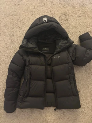 Vinterjacka - Vinterjacka från sail racing, ganska bra skick förutom att den har ett litet hål i axeln som jag bara tejpat, går att sy ihop då det inte är så stort! Säljer pga att den är för liten.