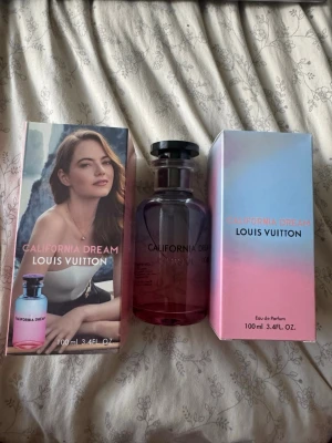 Louis Vuitton California Dream parfym - Louis Vuitton California Dream Eau de Parfum i en snygg glasflaska med blå och rosa toning. Flaskan rymmer 100 ml och har en elegant svart kork. Förpackningen har en pastellfärgad design och parfymen utstrålar lyx och modern stil.