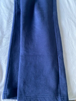 Mörkblå mjukisbyxor med dragsko - Säljer ett par mörkblå mjukisbyxor med resår i midjan och dragsko. Byxorna har raka ben och sidofickor. Tillverkade i mjukt och skönt material, perfekta för chill dagar hemma eller när du vill vara bekväm.