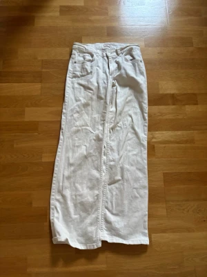 Vita raka jeans med låg midja - Säljer ett par vita jeans med rak passform och låg midja. Jeansen har klassisk femficksdesign och stängs med dragkedja och knapp. Materialet ser ut att vara bomull med lite stretch för extra komfort. Perfekta till en clean och fräsch looks.