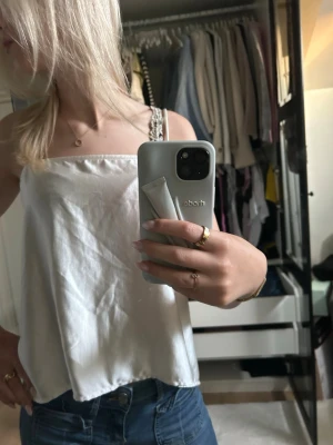 Vit linnetopp med knyt - Säljer en vit linnetopp med tunna axelband och öppen rygg som knyts baktill. Toppen har en luftig och flowy passform, perfekt för varma dagar. Styla med jeans eller kjol för en trendig look.
