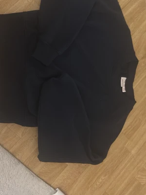 Mörkblå hoodie från Ginatricot - En enkel och stilren mörkblå hoodie från Ginatricot. Hoodien har lång ärm, rund halsringning och är gjord i mjuk bomullsmix. Perfekt för chill dagar eller när du vill ha en clean look.