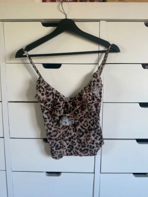 Leopardmönstrad linnetopp Stradivarius - Säljer en leopardmönstrad linnetopp från Stradivarius i storlek S. Toppen har tunna axelband, volangdetaljer framtill och är i ett lätt, luftigt material. Perfekt för dig som vill sticka ut med ett djurmönster och gillar trendiga detaljer.
