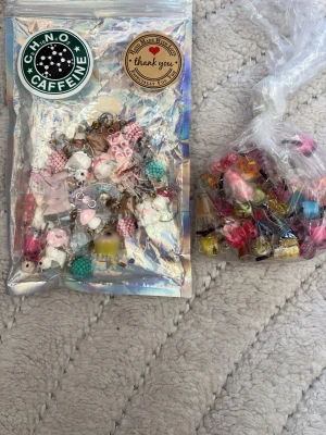 Massa berlocker  - Stort paket med mixade berlocker och charms i plast och resin, många i pastellfärger och former som djur, drycker, godis och frukter. Perfekt för att pyssla egna smycken eller dekorera mobilskal. Färgglada och lekfulla detaljer för dig som gillar kawaii-stil.