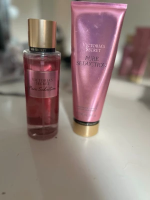 Victoria's Secret Pure Seduction set - Säljer ett Victoria's Secret Pure Seduction set med en rosa parfymmist och en matchande body lotion. Båda har guldiga detaljer och ger en fräsch, feminin doft. Perfekt för dig som gillar söta och fruktiga toner.
